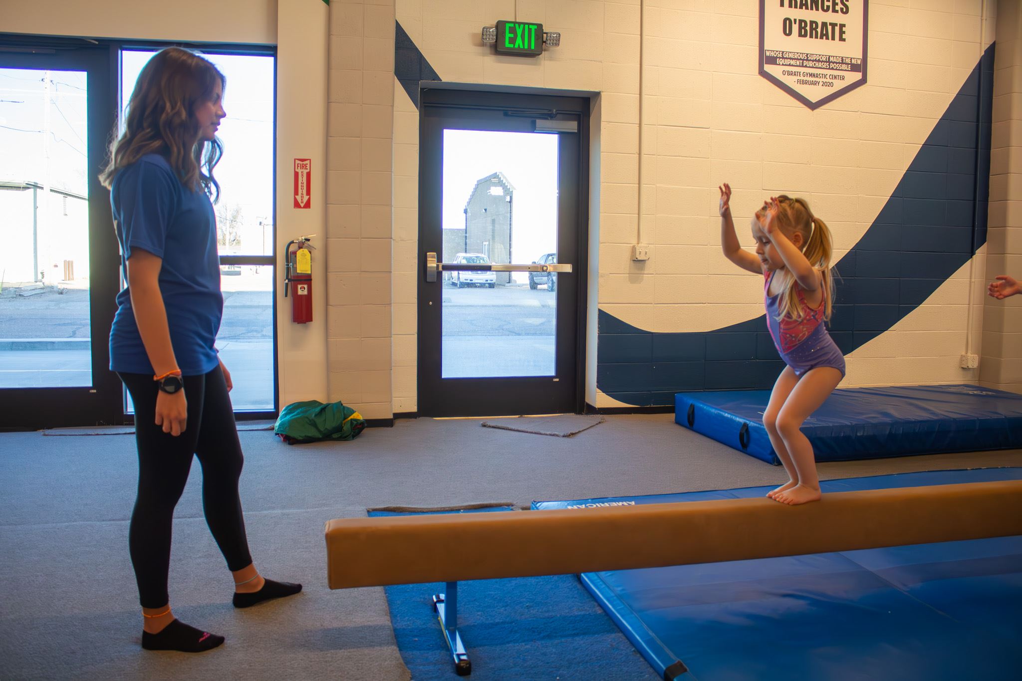Gymnastics coach is helping gymnast on Beam